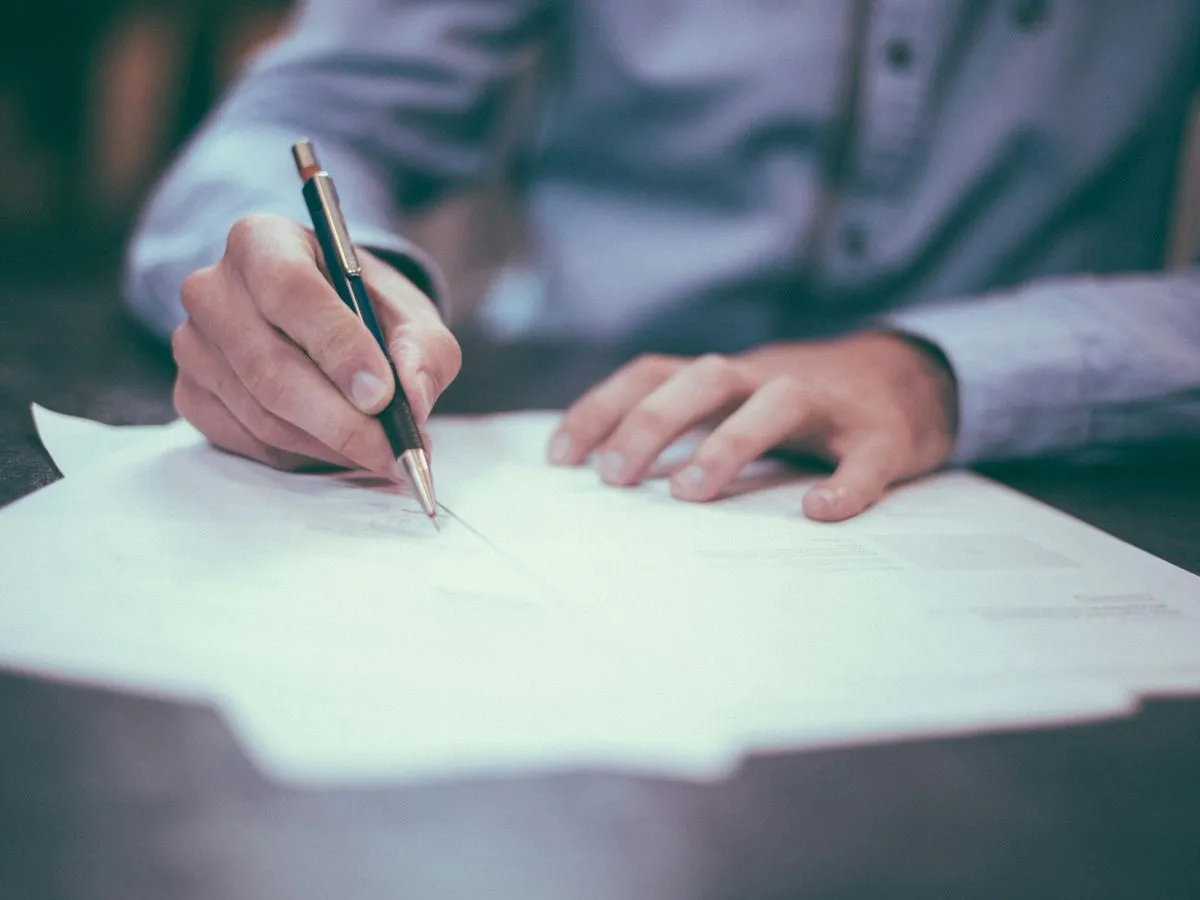 Hand signing a printed document with a pen