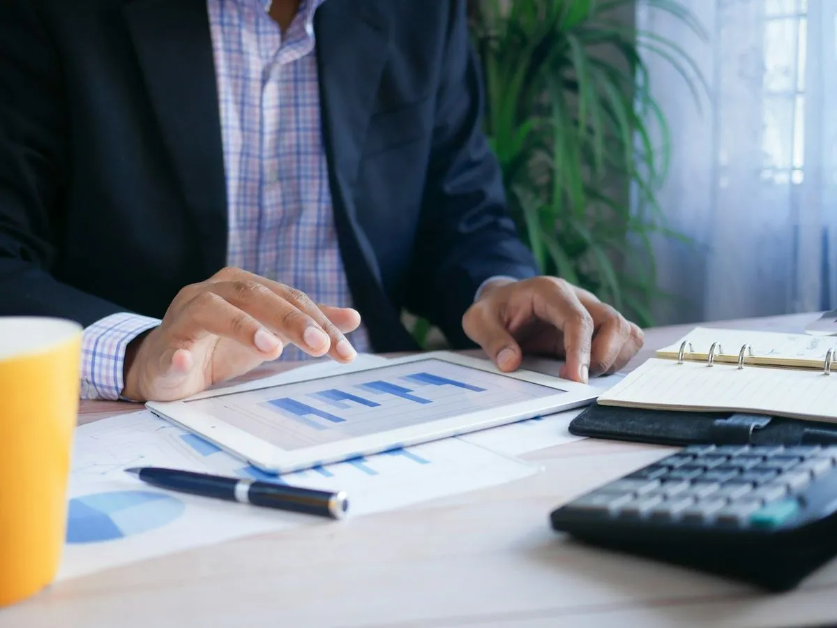 Accountant reviewing figures on a tablet beside a calculator and documents