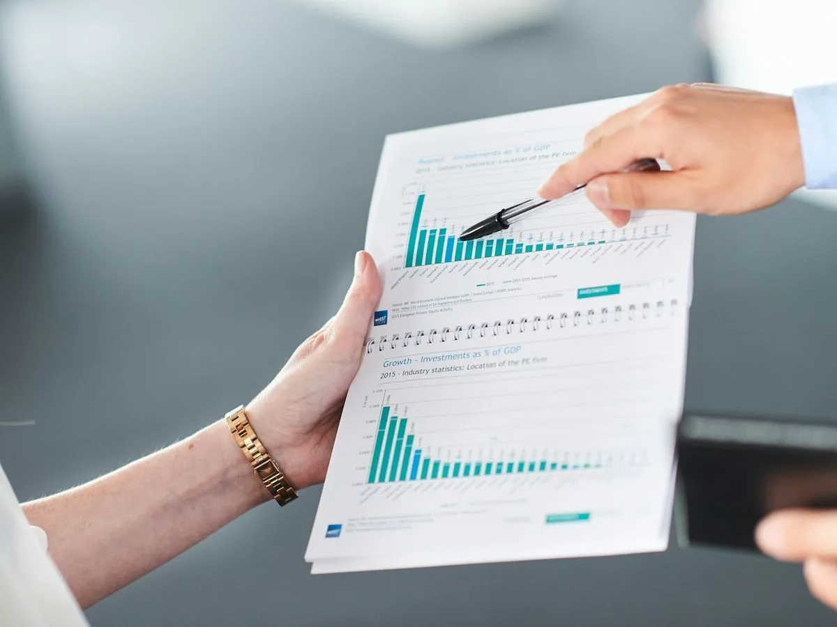 Two people reviewing a printed financial report with charts