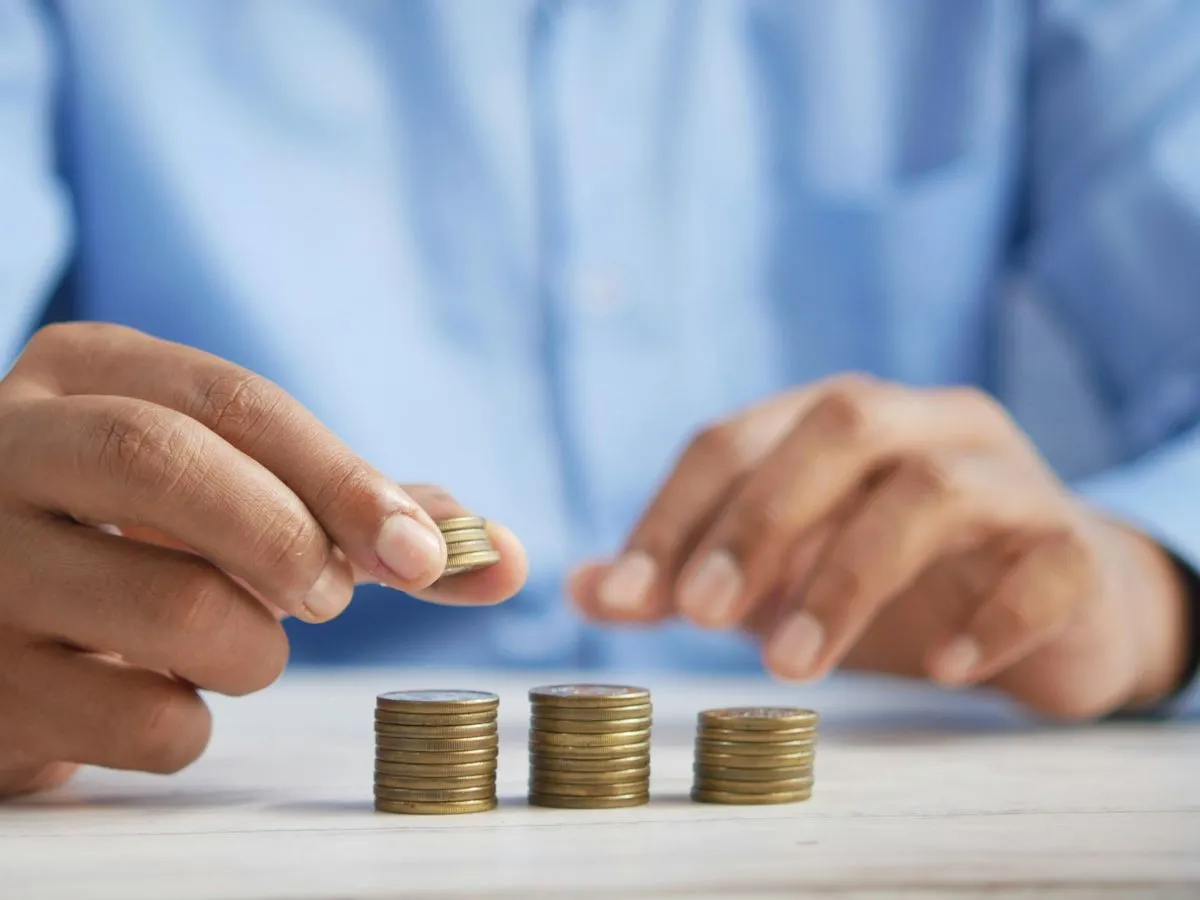 Hands stacking coins into neat piles on a table