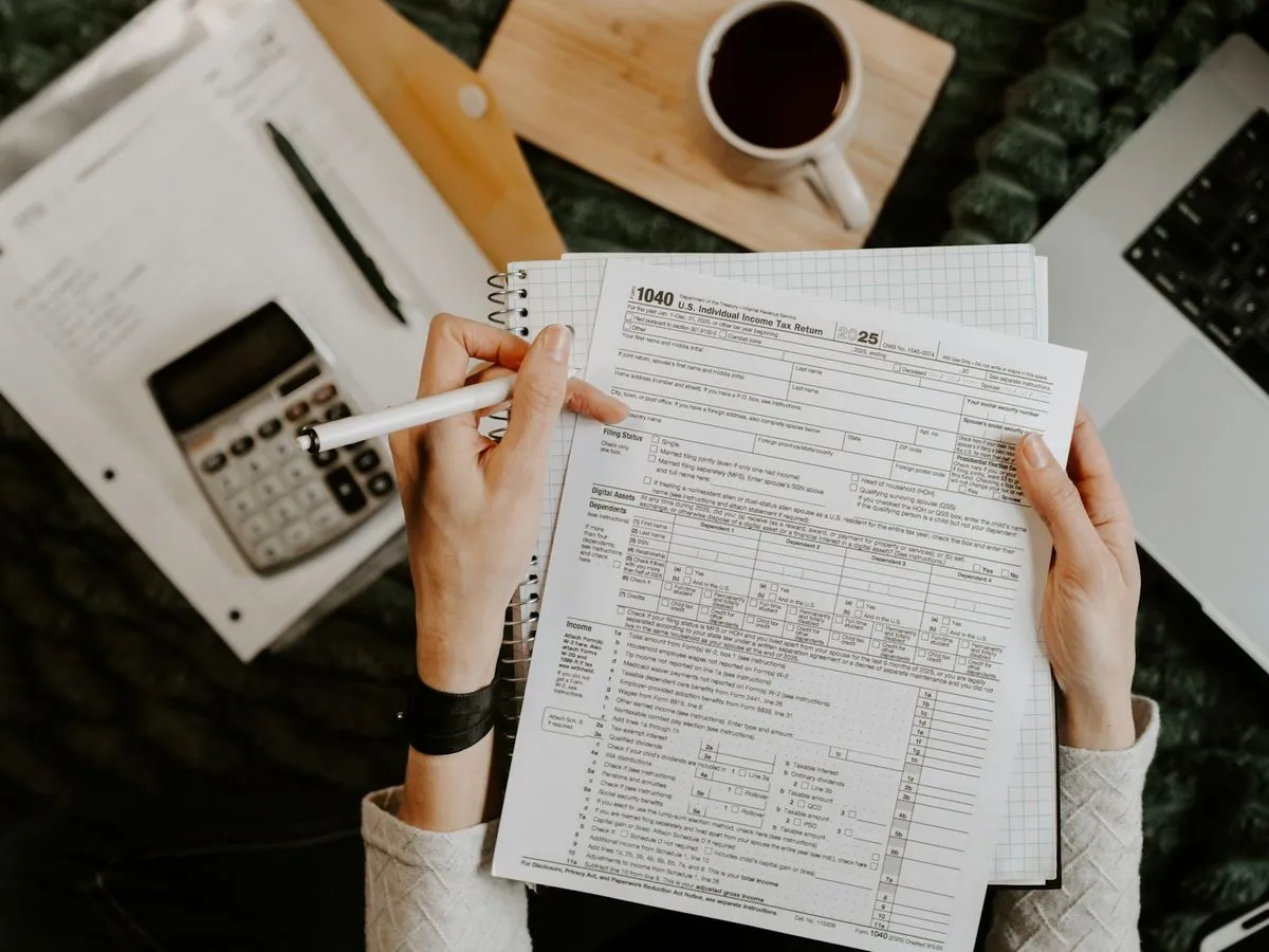 Person checking forms against a calculator with a pen in hand